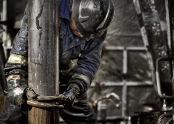 Oil Rig Worker wearing his safety gear working on the muddy drill floor   Trabalhador de plataforma petrolífera usando seu equipamento de segurança trabalhando no chão de perfuração lamacento